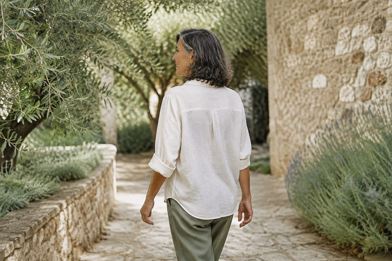 Mujer caminando por un jardín mediterráneo; escena ilustrativa de bienestar cotidiano