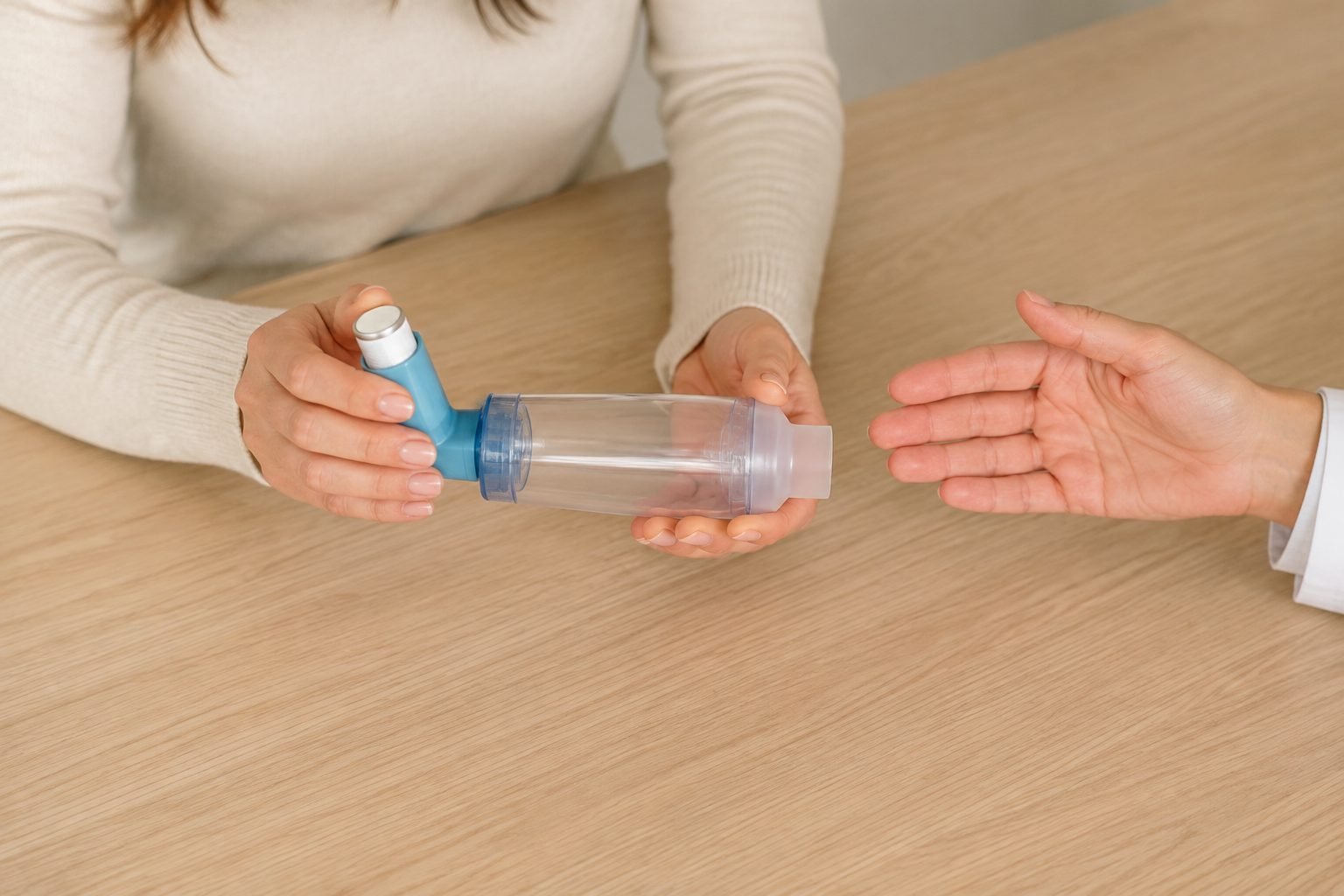 Detalle de un inhalador y una cámara espaciadora durante una explicación; escena ilustrativa